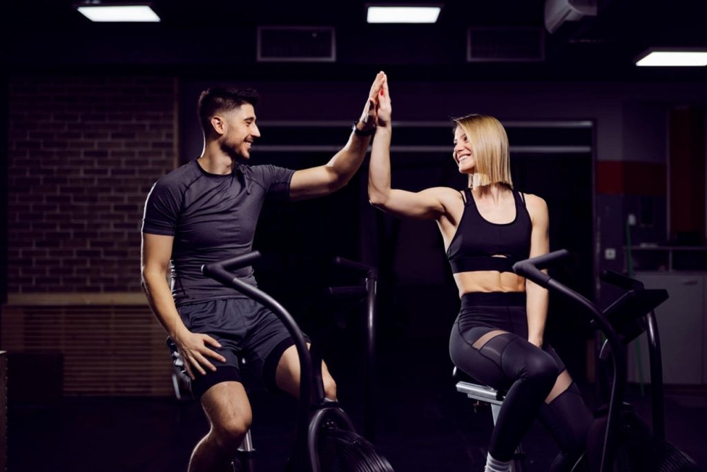 Spor salonunda antrenman sırasında birbirine destek olan ve yüksek motivasyonla çalışan fitness çifti.